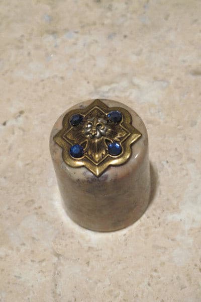 Jeweled trinket box with gold fleur-de-lis and blue gemstones on marble surface