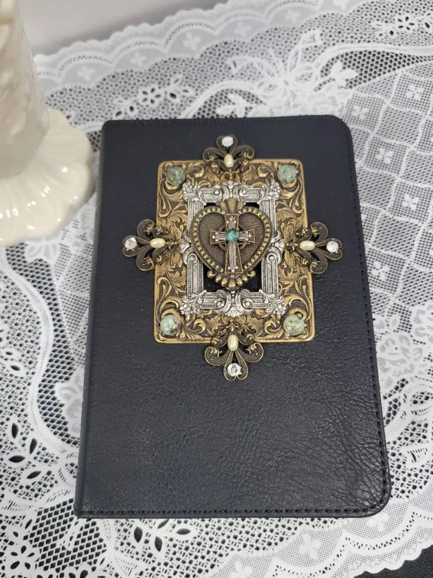 Handcrafted jeweled Bible with ornate cross and heart embellishment on black cover, lace background