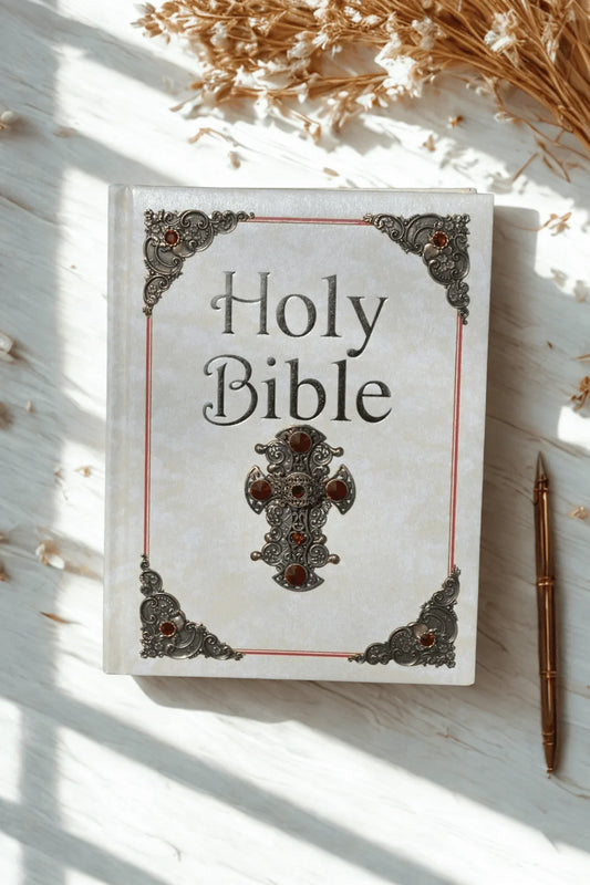 Handcrafted jeweled Holy Bible with ornate metal accents on a white desk with dried flowers