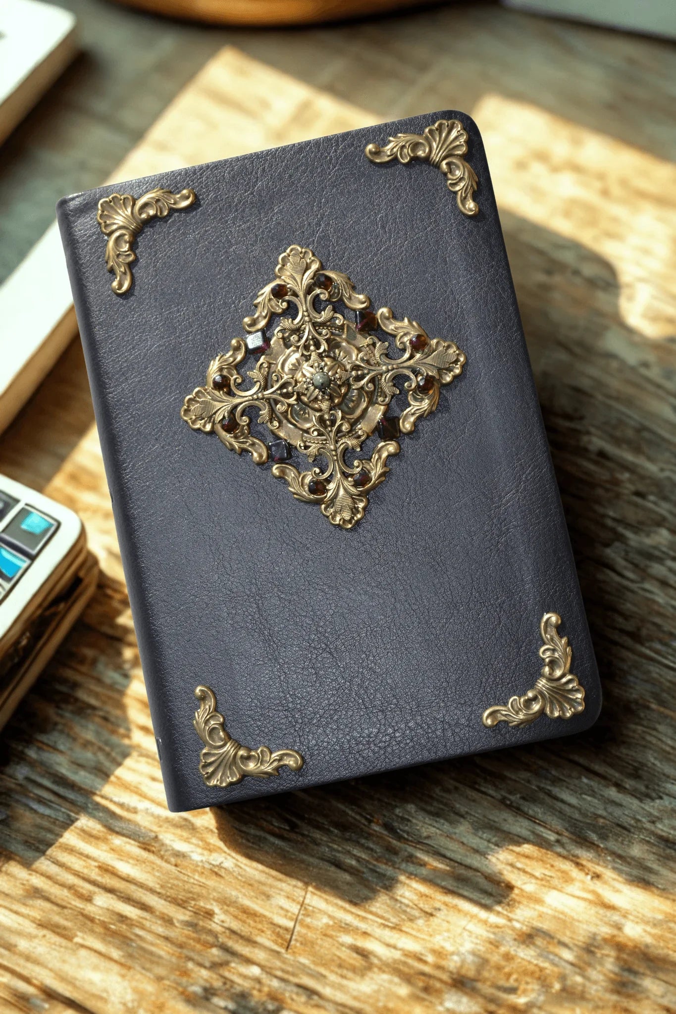 Dark leather Bible with ornate gold filigree and jeweled embellishments on wooden table
