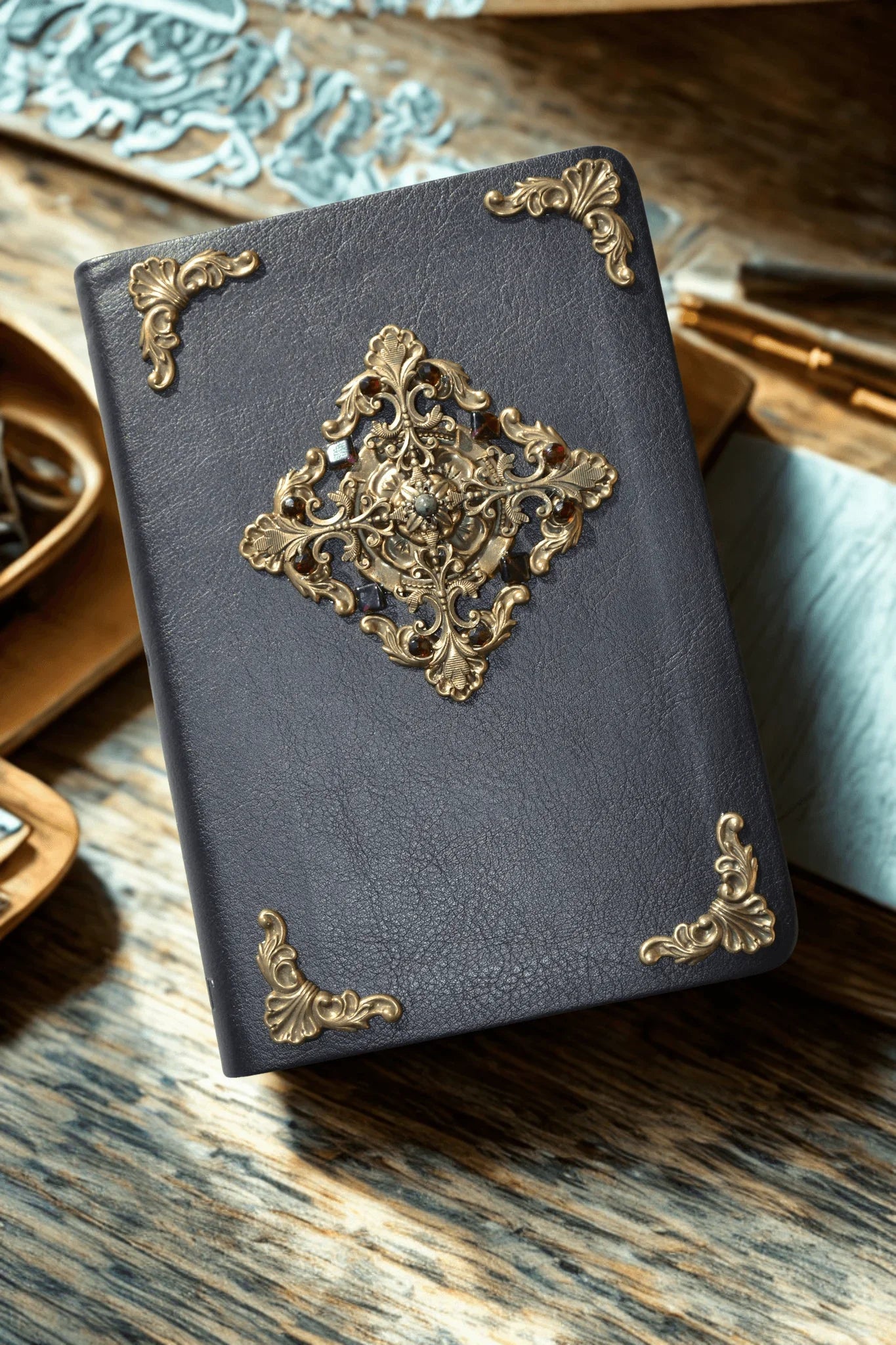 Jeweled leather Bible with ornate gold filigree and decorative metal corners on wood table
