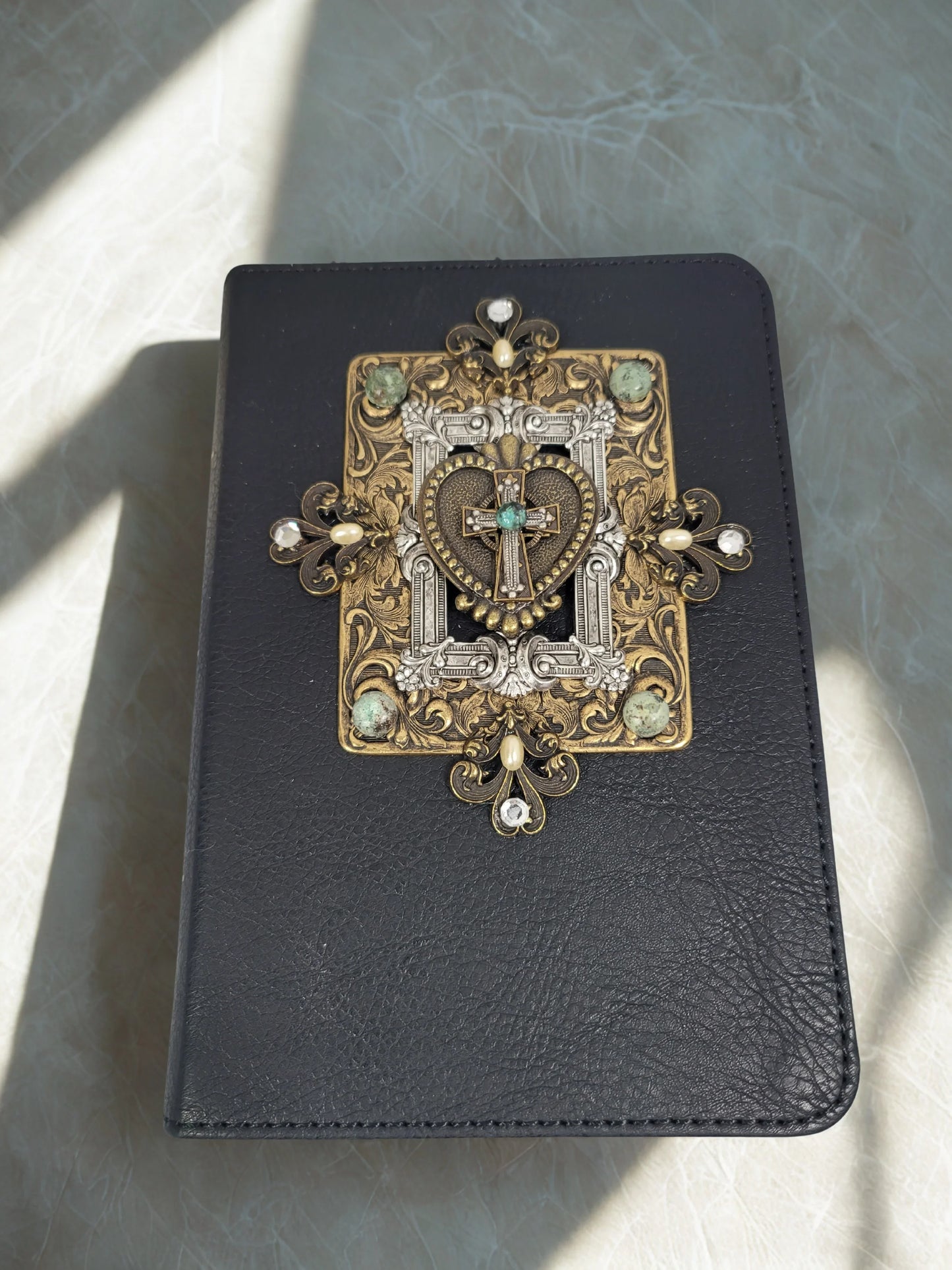 Black leather Bible with ornate gold and silver jeweled cross and heart embellishment