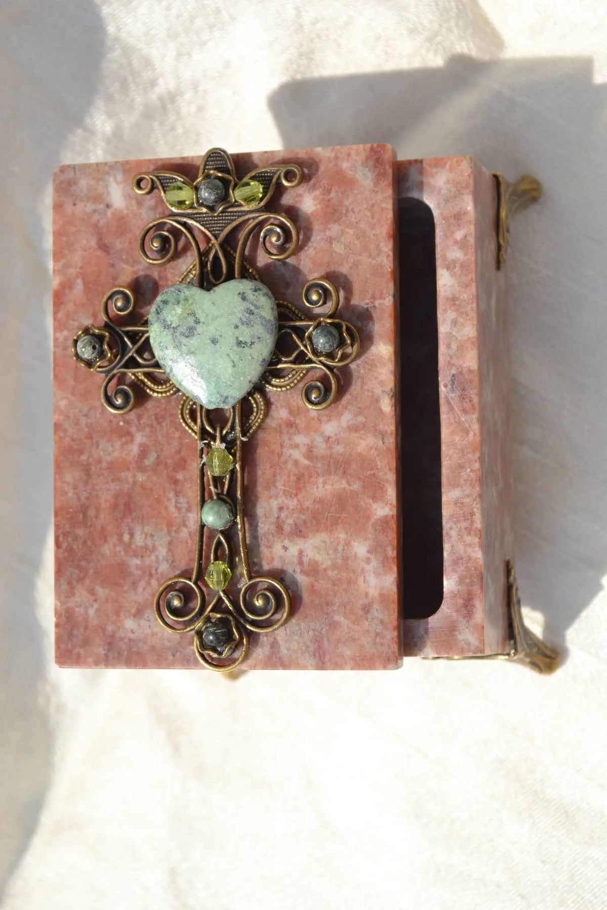 Jeweled soapstone keepsake box open, adorned with a green heart gemstone cross.