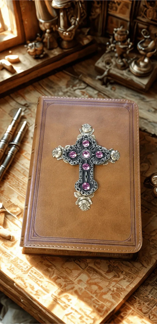Tan leather baby keepsake Bible with jeweled cross and pink gemstones on a carved table