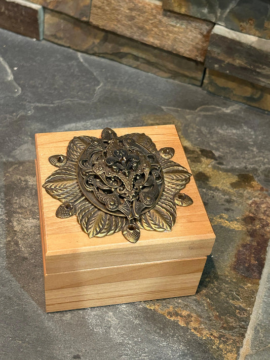 French-inspired wooden keepsake box with ornate metal floral embellishment, top view