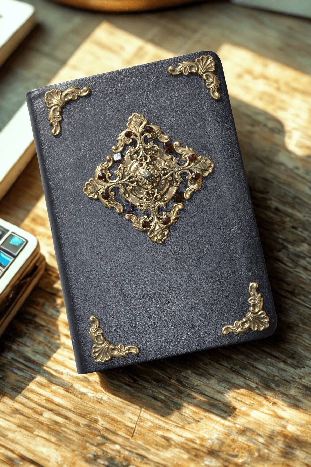 Dark leather Bible with ornate gold filigree and jeweled embellishments on wooden table