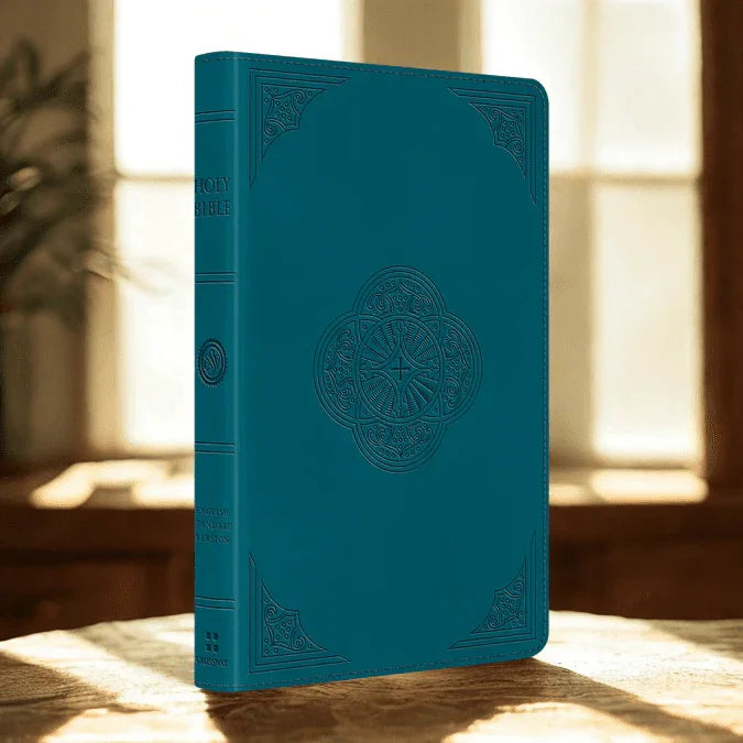 Teal leather ESV thinline Bible with embossed design on a sunlit table by a window.