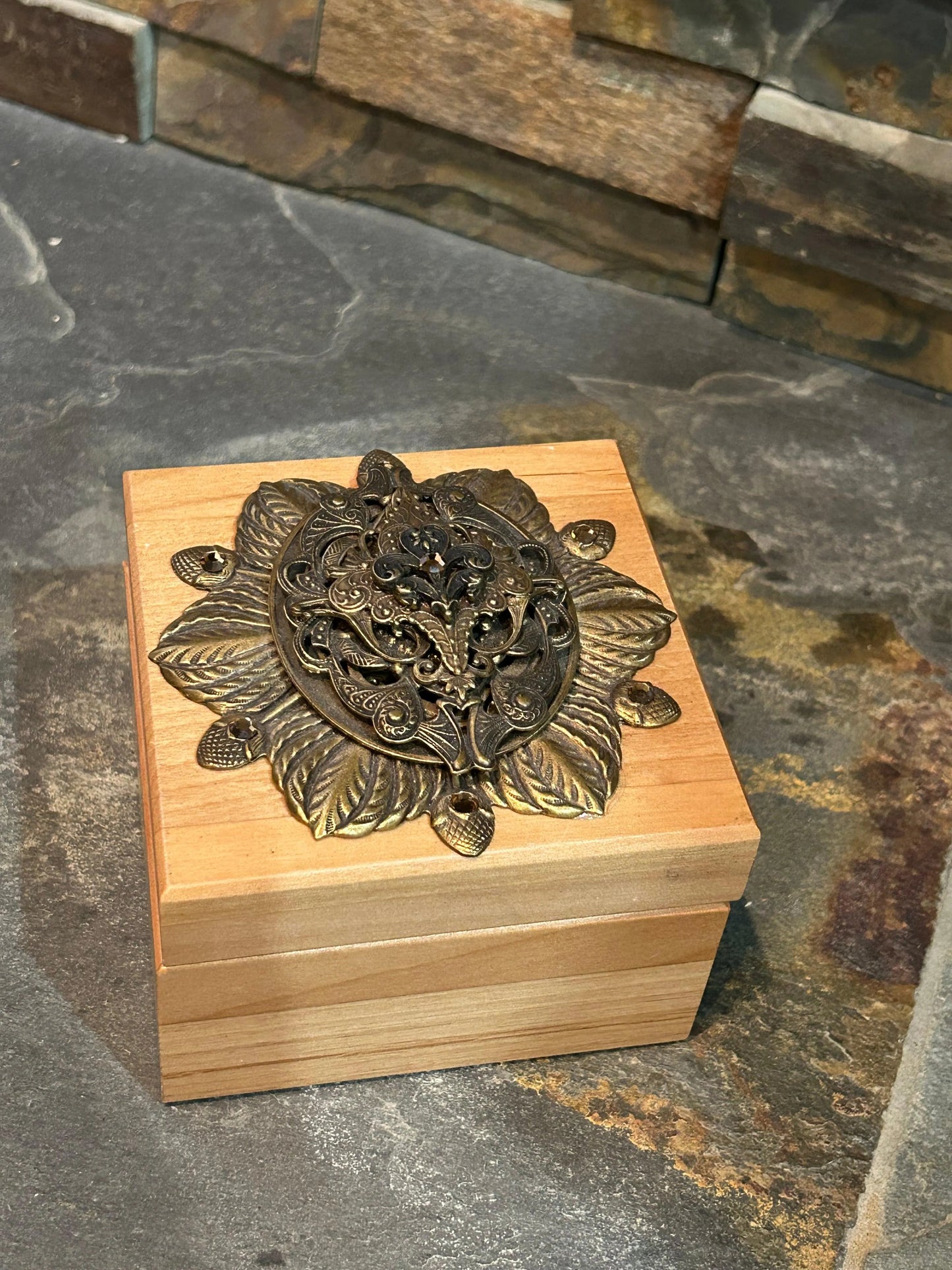 French-inspired wooden keepsake box with ornate metal floral embellishment, top view