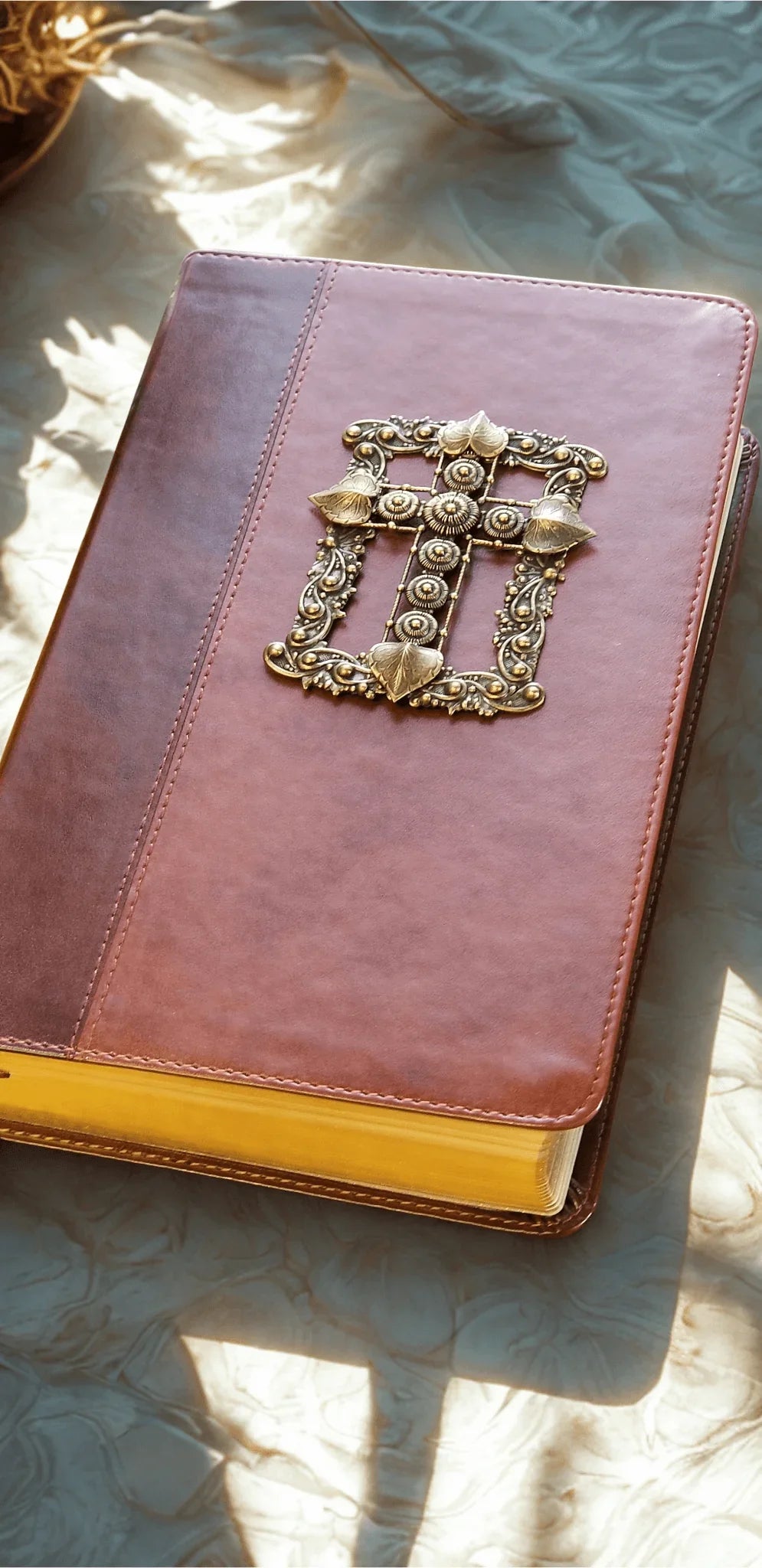 Brown leather Bible with jeweled cross embellishment and gold-edged pages on table