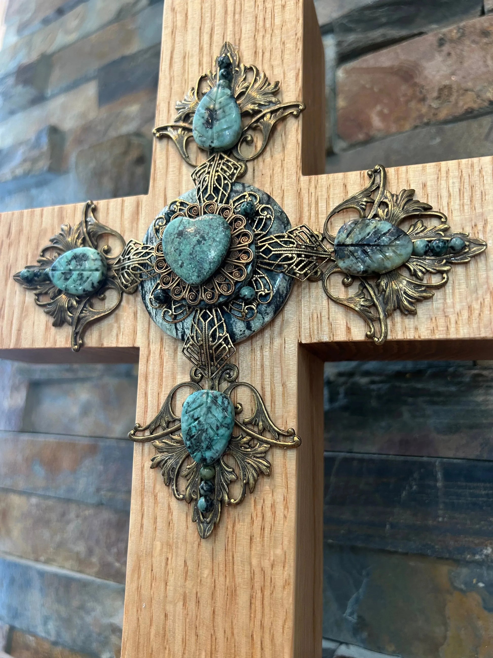 Handcrafted wooden cross with ornate metalwork and turquoise stones, close-up detail