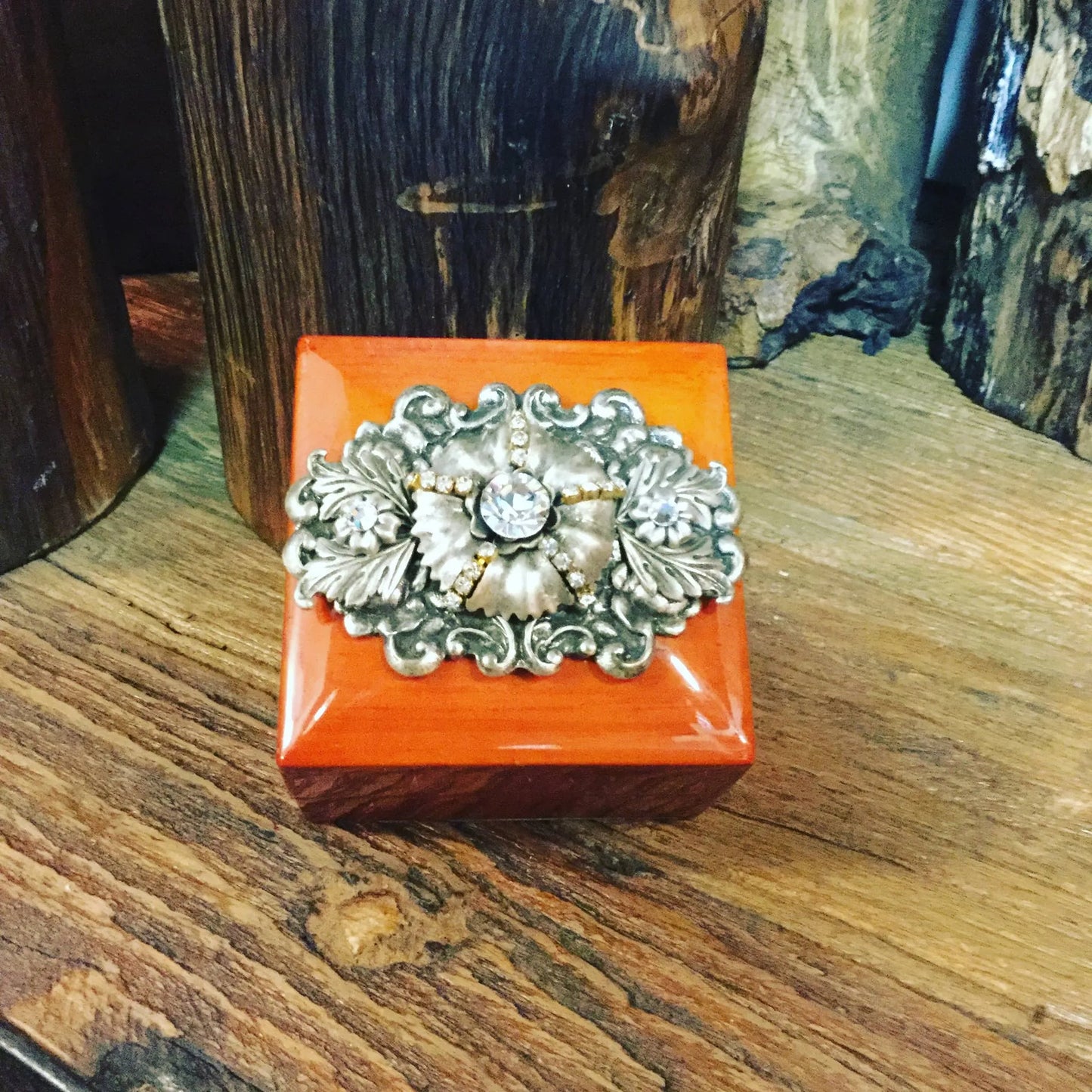 Handcrafted wood ring box with ornate silver and gemstone accent on rustic wood surface