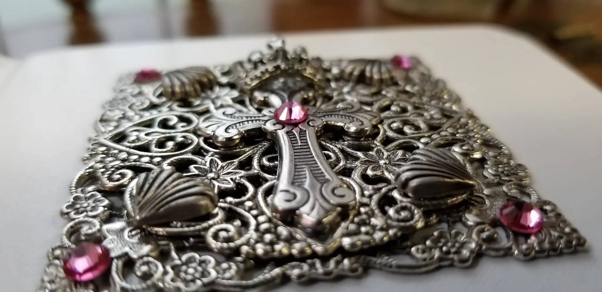 Jeweled silver baby keepsake Bible cover with ornate metal cross and pink gemstones