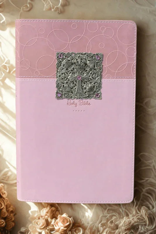 Jeweled pink baby keepsake Bible with ornate silver cross detail, in natural light.