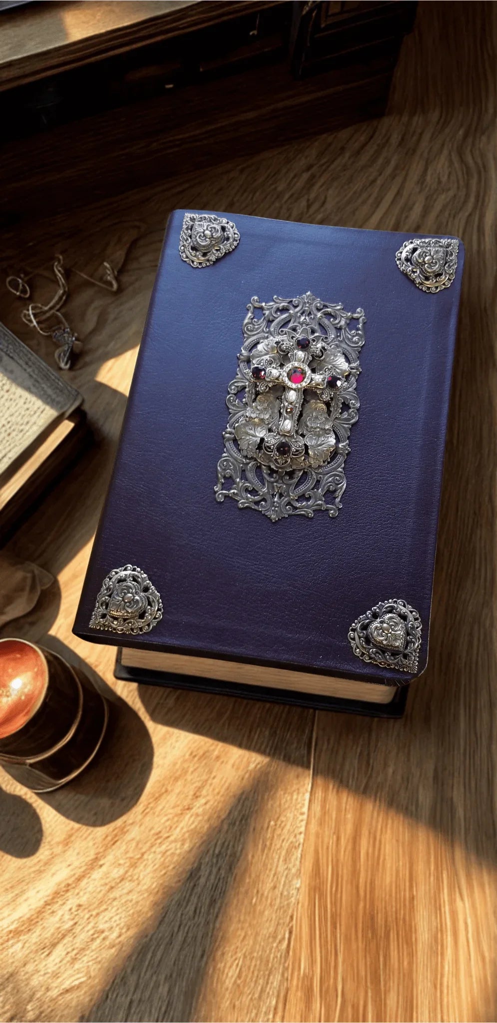 Jeweled Bible with ornate silver cross and brass accents on dark cover, tabletop view