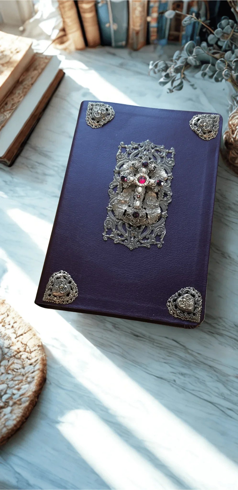 Jeweled Bible with ornate brass accents and center cross on purple cover, close-up view.