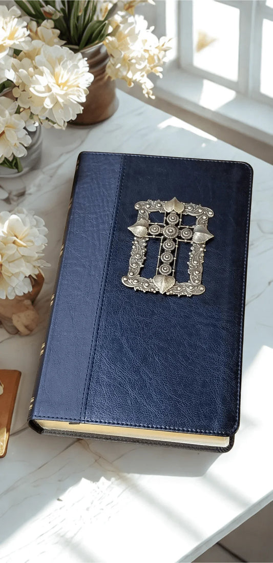 Black leather jeweled Bible with ornate silver cross, surrounded by white flowers on table