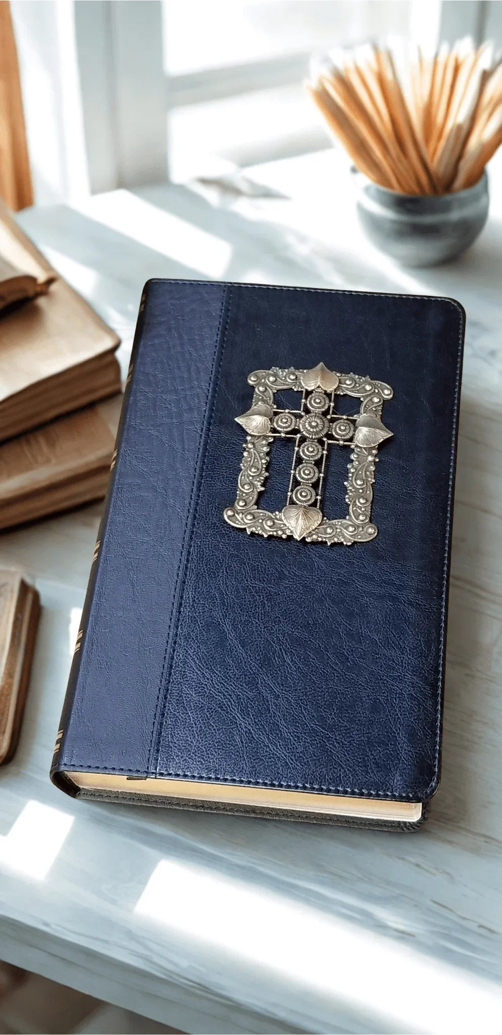 Jeweled KJV Bible with ornate silver cross on dark leather cover, on a sunlit table
