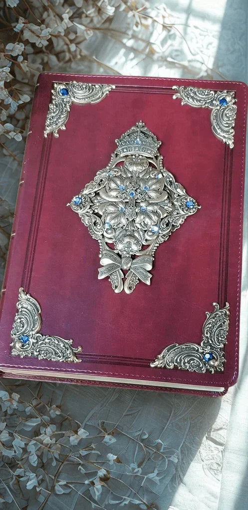 Jeweled KJV Bible with ornate silver and blue accents on burgundy cover, displayed with flowers
