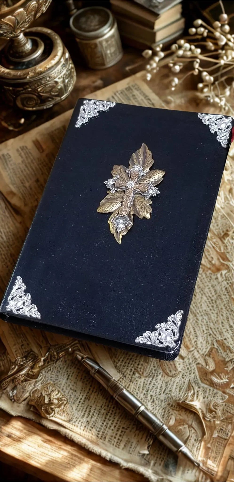 Jeweled black Bible with ornate gold leaf cross and silver filigree corners on vintage desk