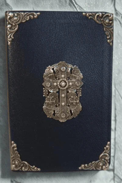 Jeweled black Bible with rhinestone cross and ornate gold corners on marble surface