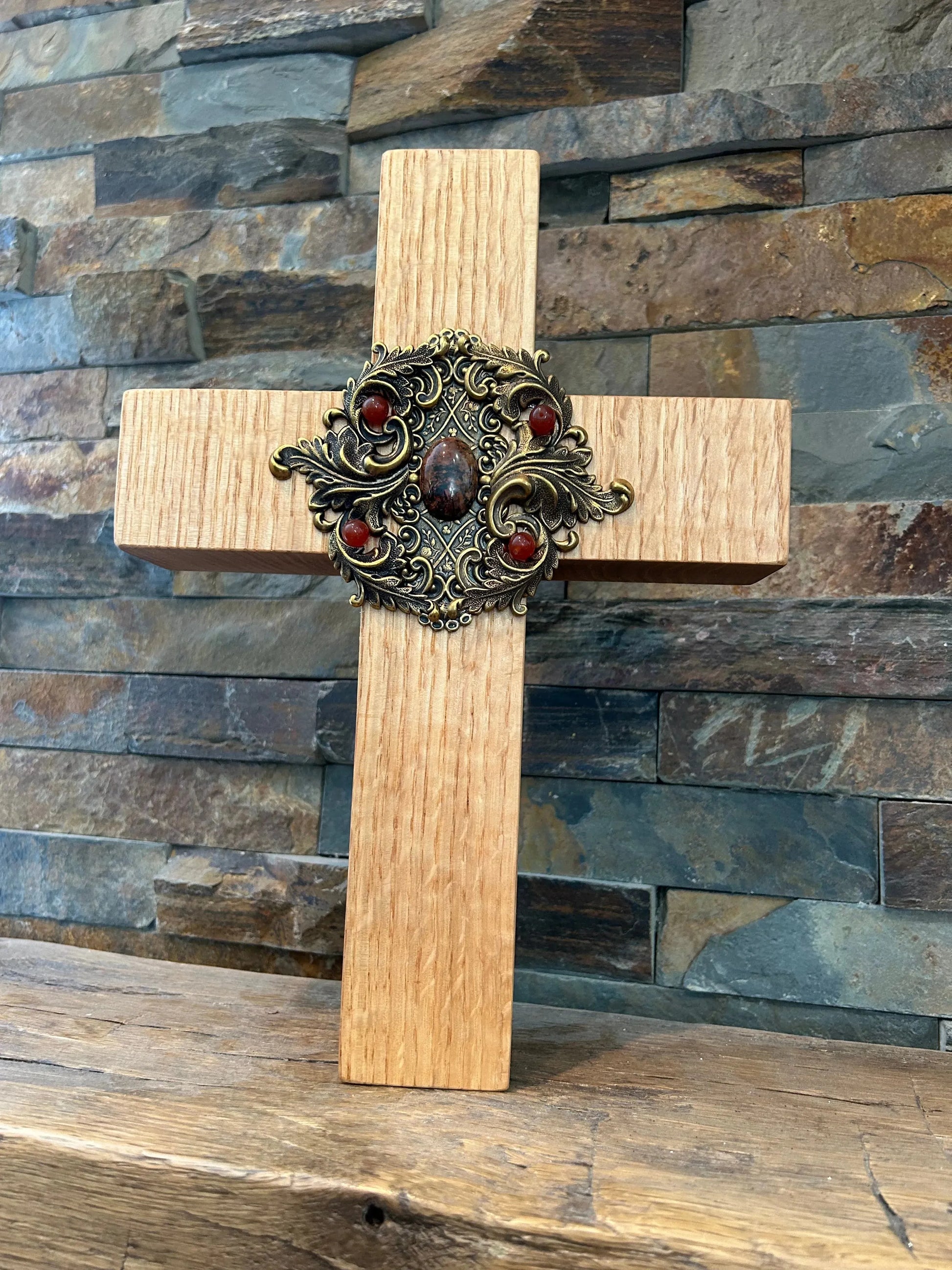 Jeweled oak cross with ornate metal centerpiece for home decor, set against a stone wall