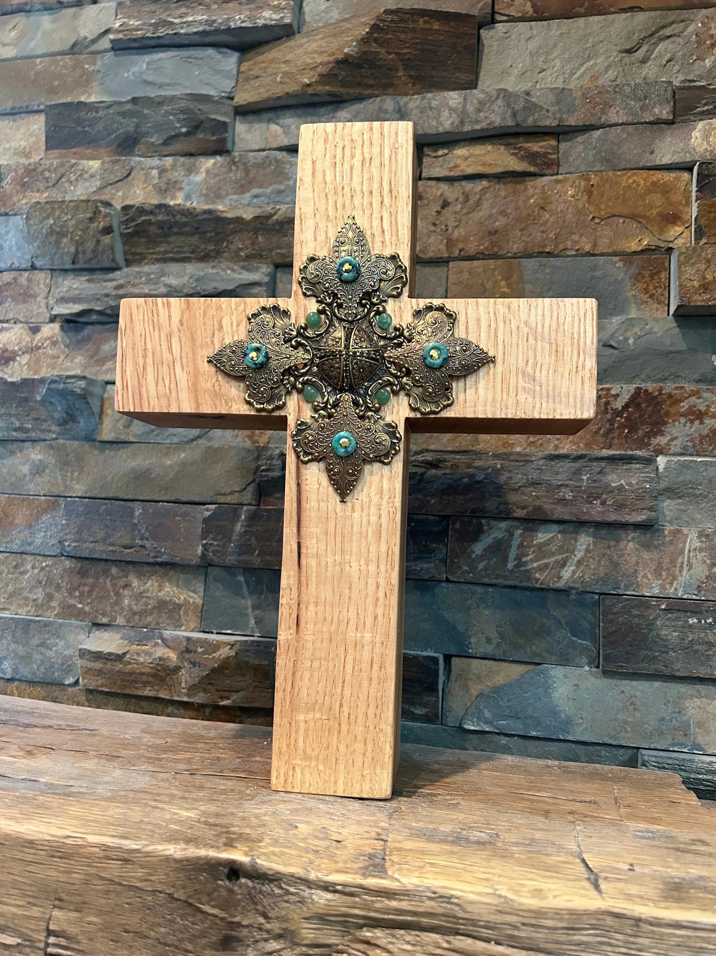 Handcrafted oak cross with ornate metal and turquoise embellishments on rustic wood