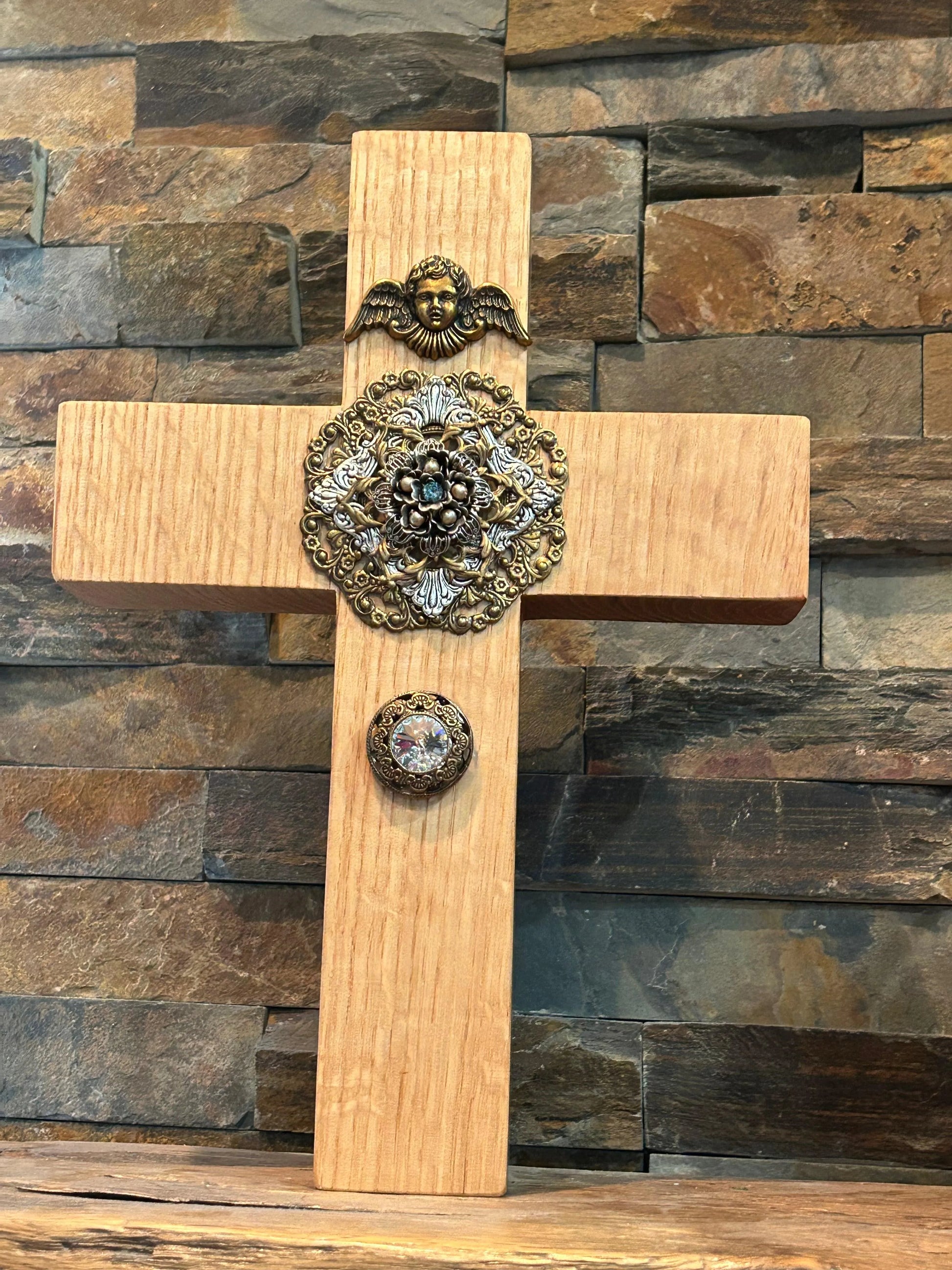Jeweled oak cross wall decor with ornate angel and central crystal embellishments against stone background