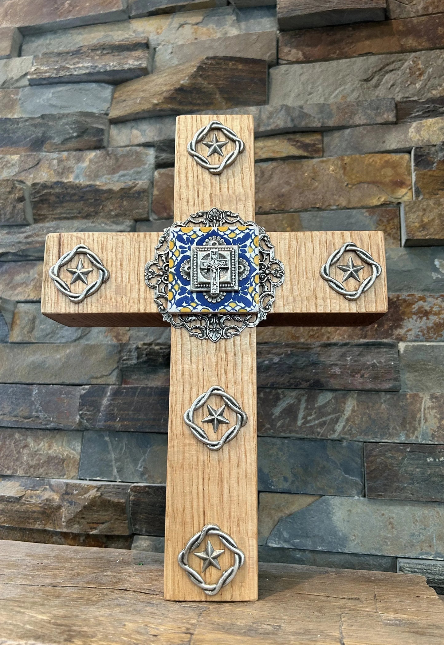 Artisan wood cross with jeweled metal accents and star ornaments, rustic stone background