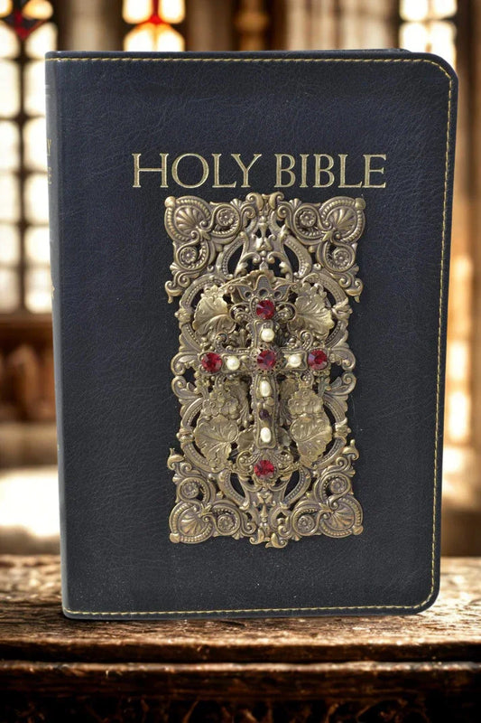 Jeweled Holy Bible with ornate gold filigree and red gemstones on black leather cover indoors