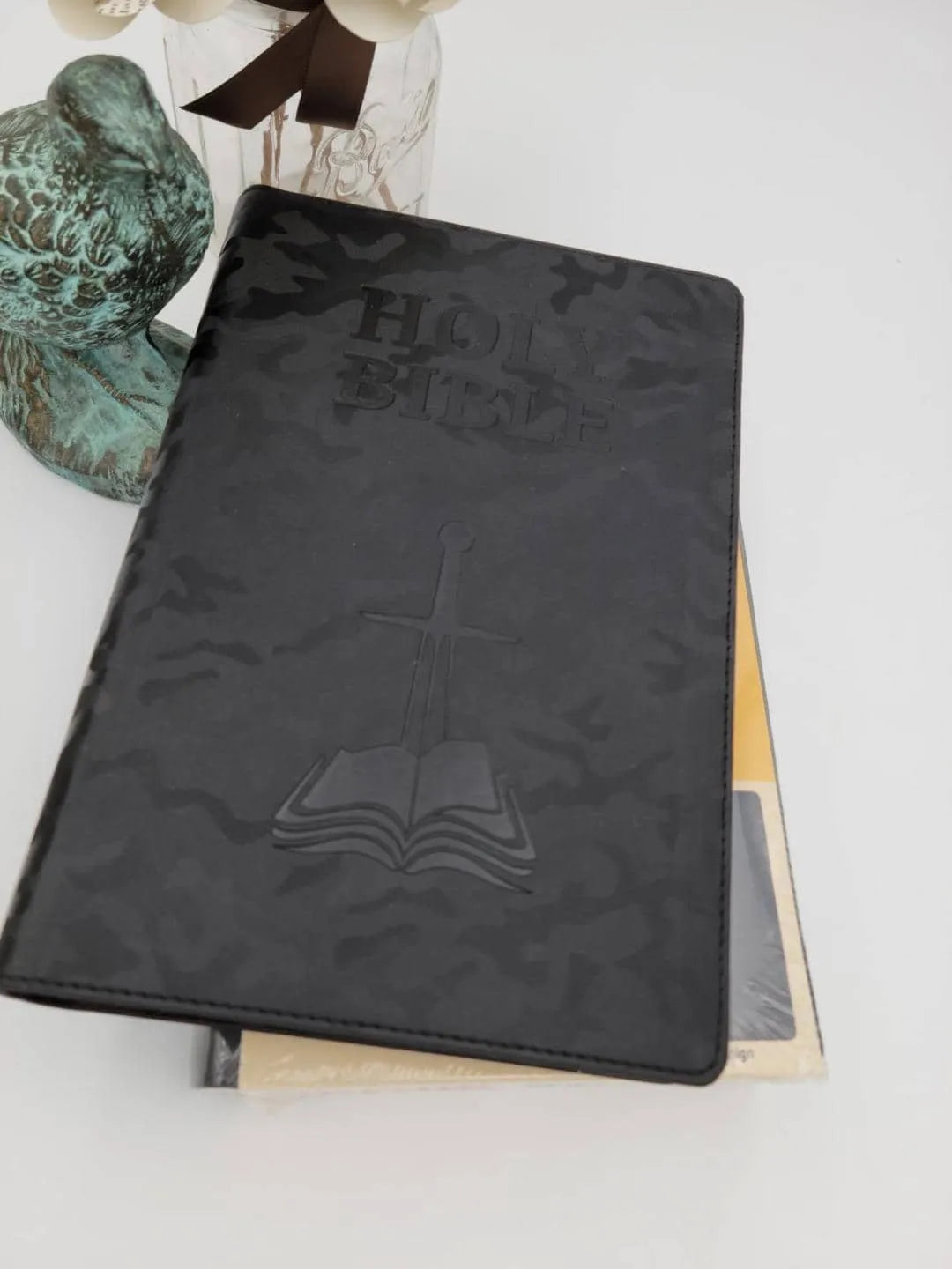 Black NASB 1995 children's Bible with embossed cross and book, next to decorative objects