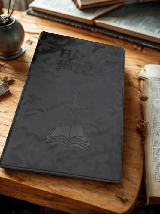 Black embossed children's Bible on wooden table with open books in background