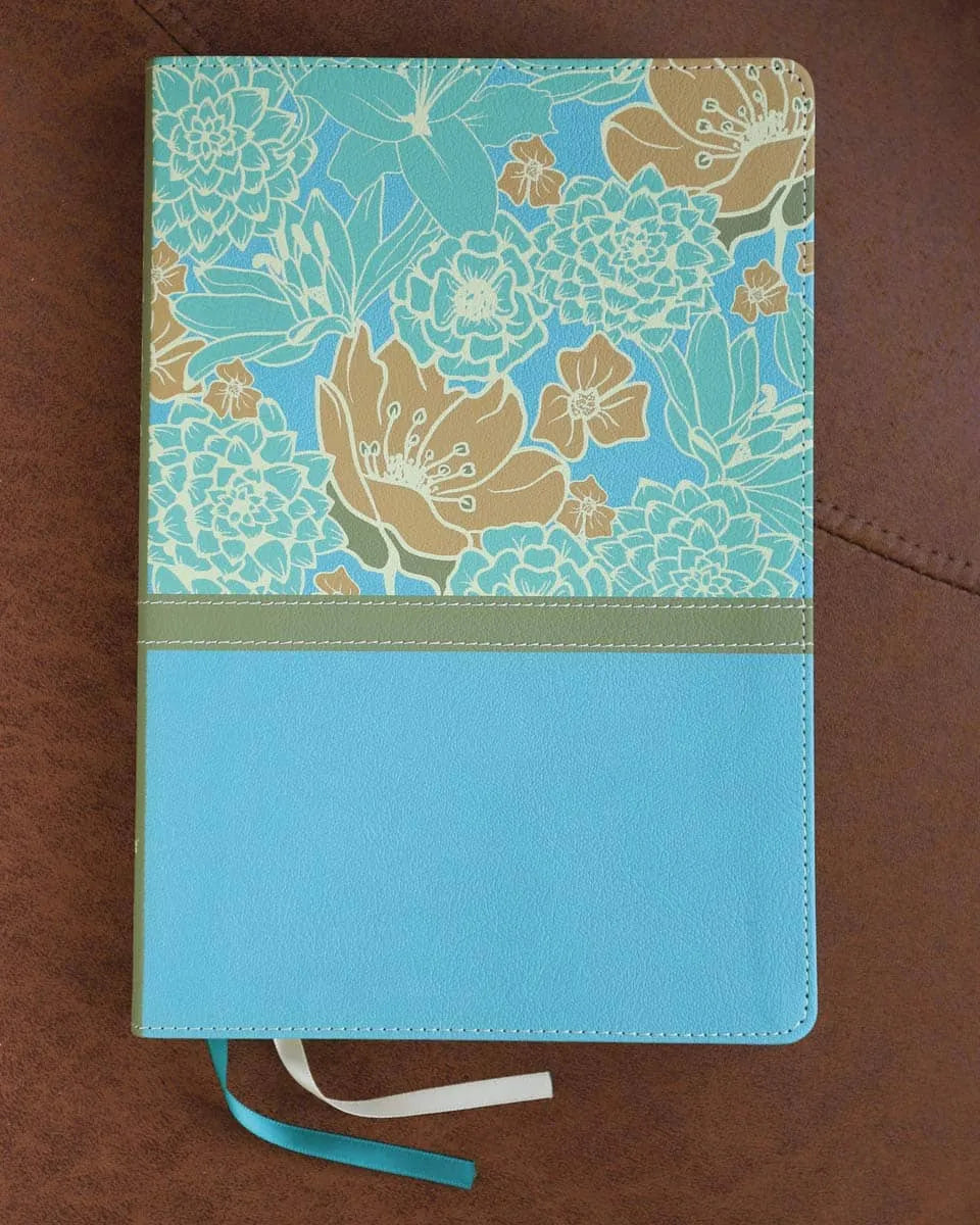 Large print Bible with blue and cream floral cover, flat lay on brown surface