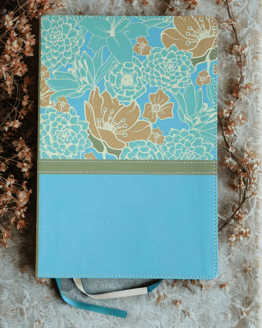 Large print Bible with blue and cream floral cover, faux leather, flat lay on lace cloth