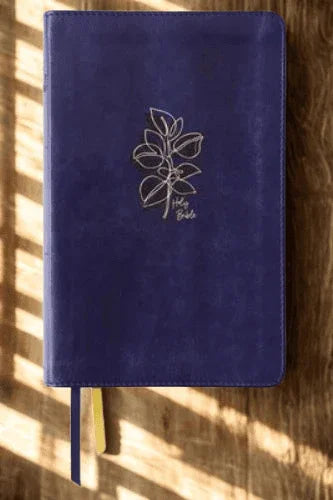 Navy leather devotional Bible with embossed floral design on wooden surface