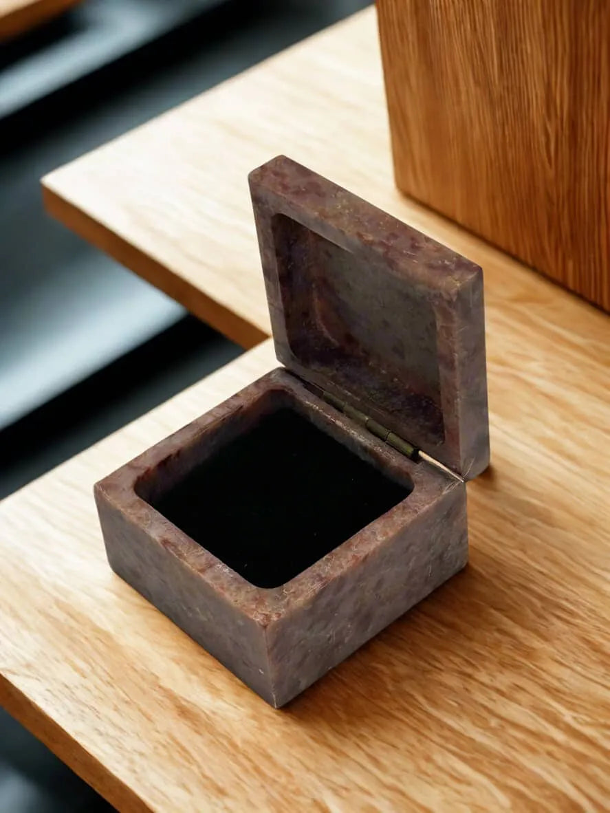 Open stone ring box with dark velvet interior on a wooden surface