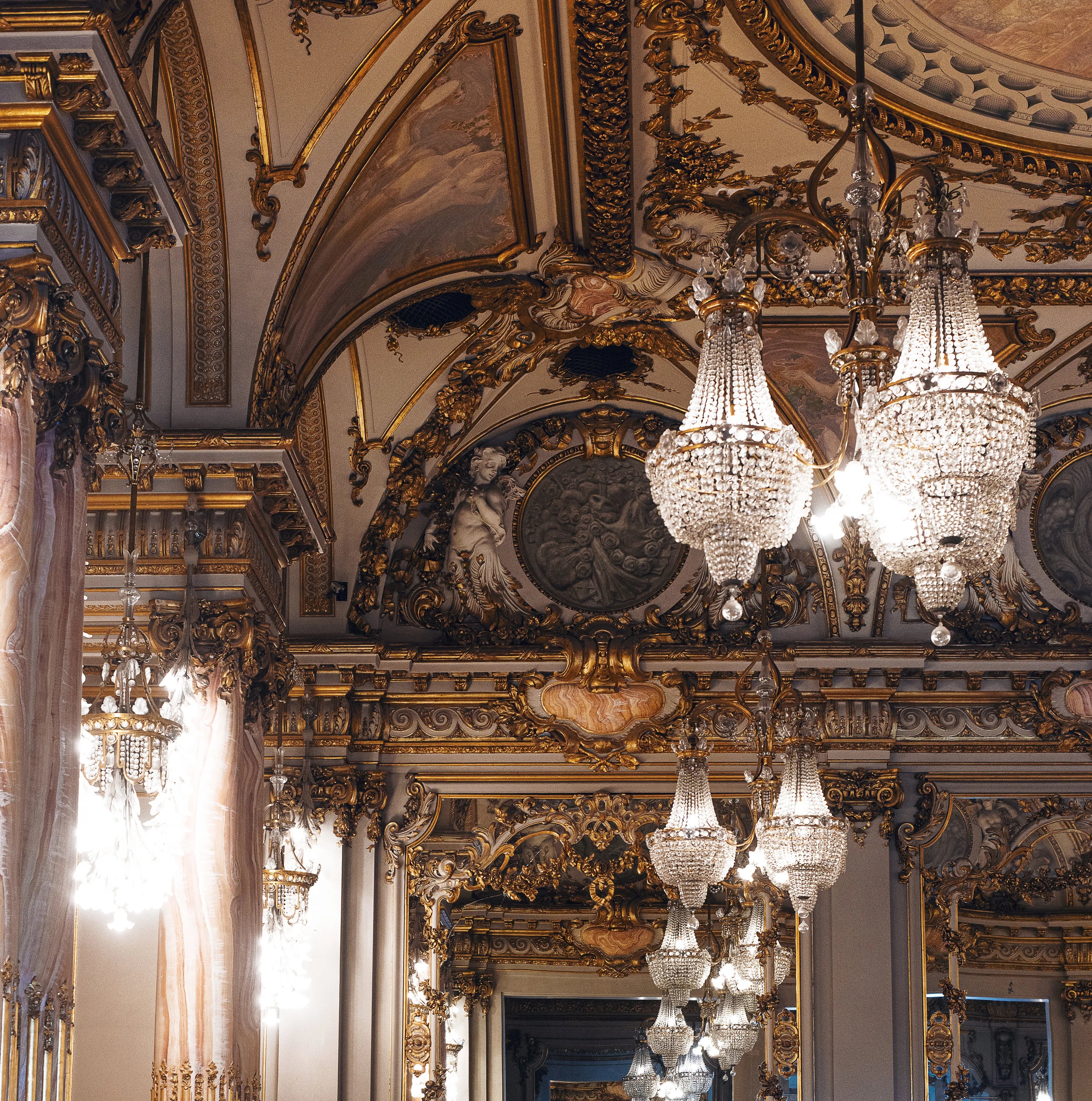 Opulent hall with ornate gold decor and glittering crystal chandeliers