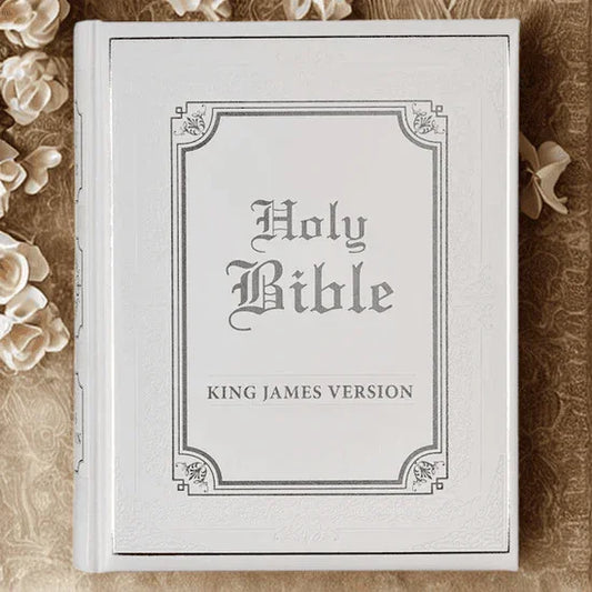 White faux leather King James Bible with ornate cover, styled on an elegant fabric with flowers