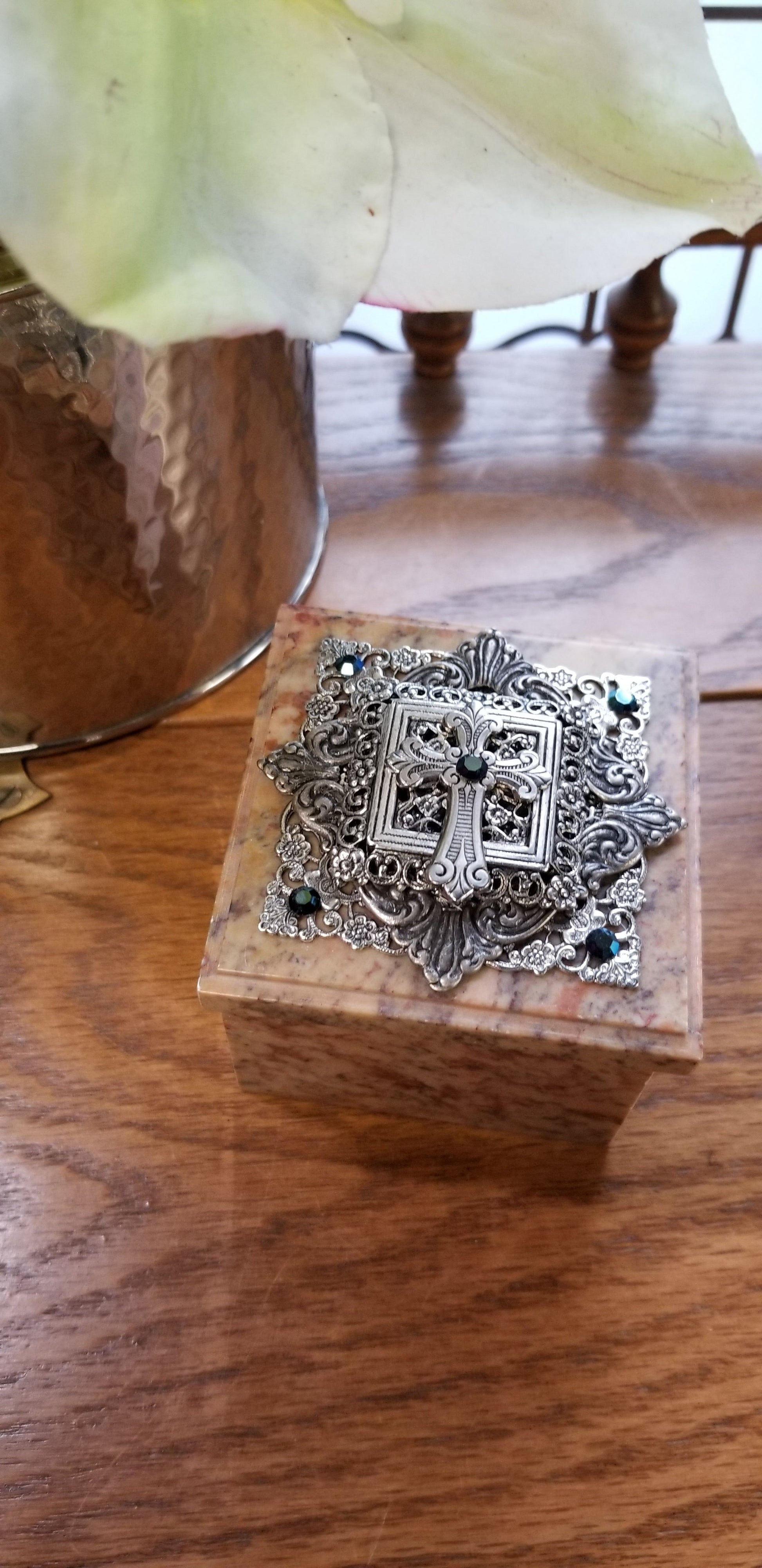 Marble keepsake box with ornate silver cross lid on a wooden surface