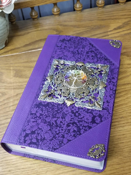 Purple floral giant print Bible with ornate metal tree of life detail on wood table