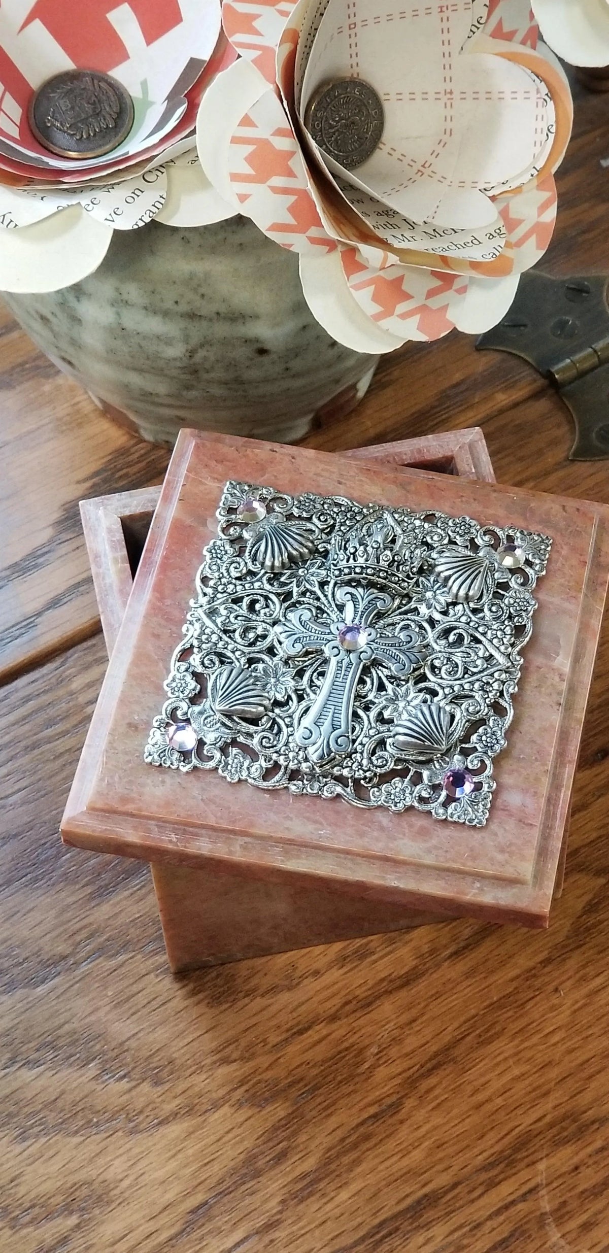 Jeweled metal cross baby keepsake box with ornate detailing and purple gemstones on wood table