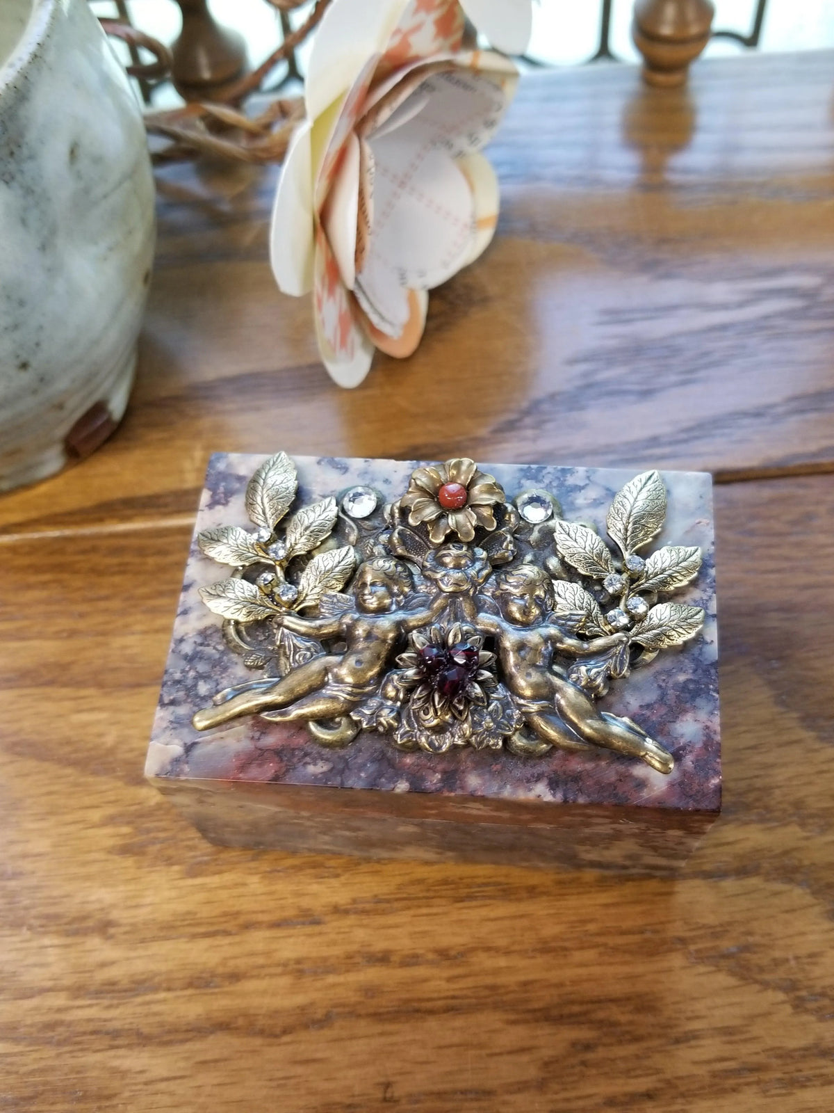 Soapstone keepsake box with bronze cherub and floral design on wooden surface