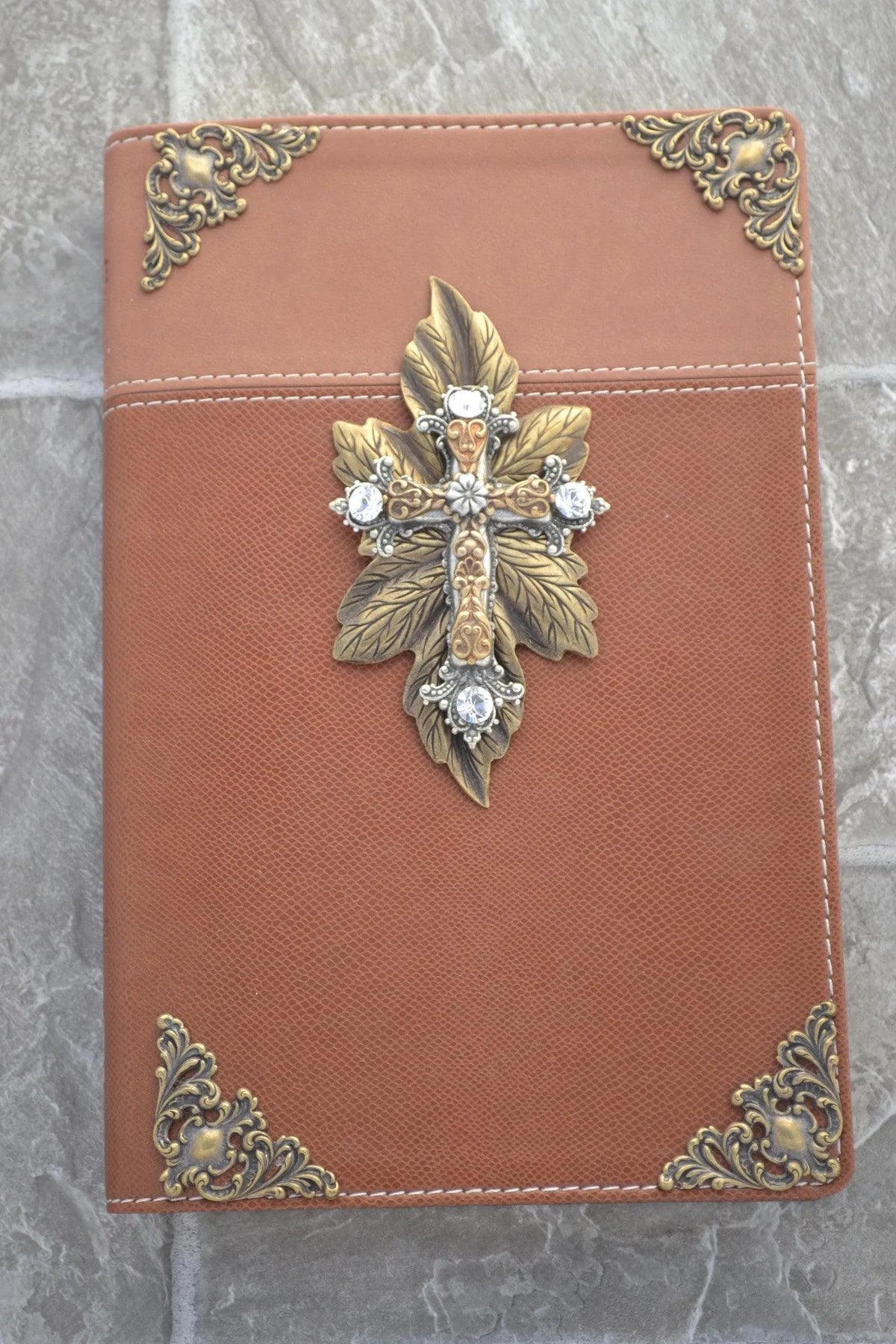 Brown Bible with jeweled gold cross, ornate metal corners, and leaf accents on cover