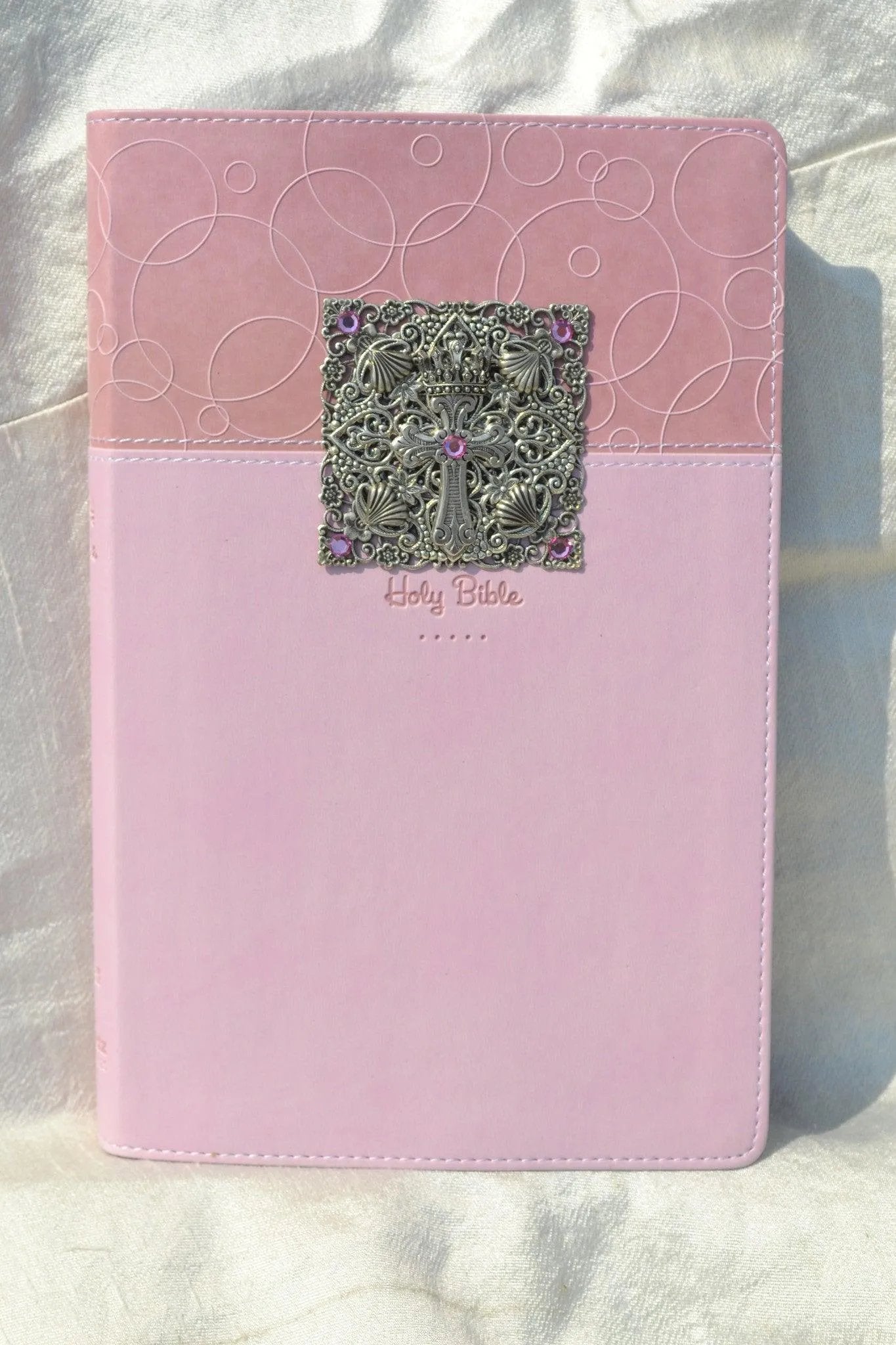 Pink baby keepsake Bible with ornate jeweled silver cross and pink gemstones on cover