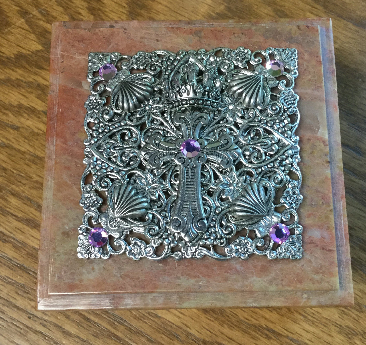 Jeweled baby keepsake box with ornate metal cross and purple gemstones on marble lid