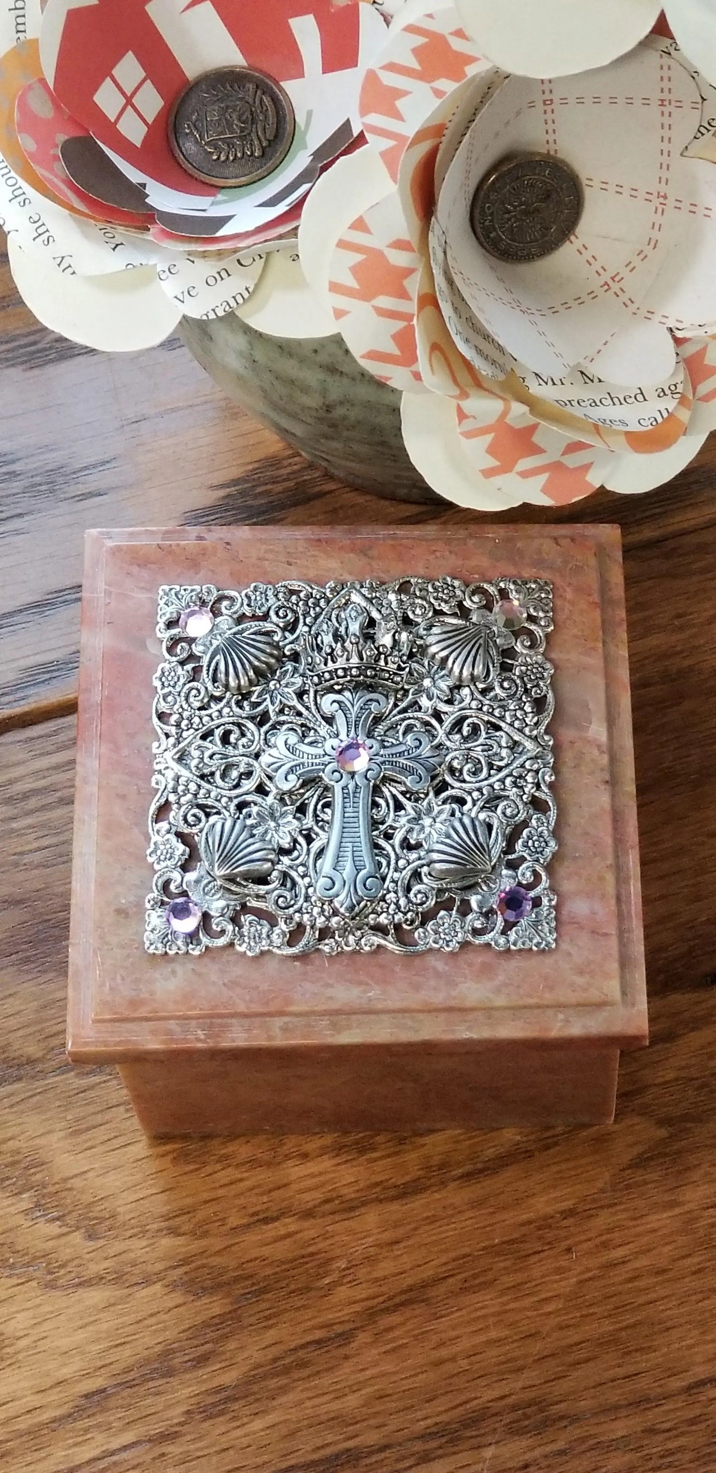 Ornate jeweled baby keepsake box with metal cross and purple gemstones on wood table
