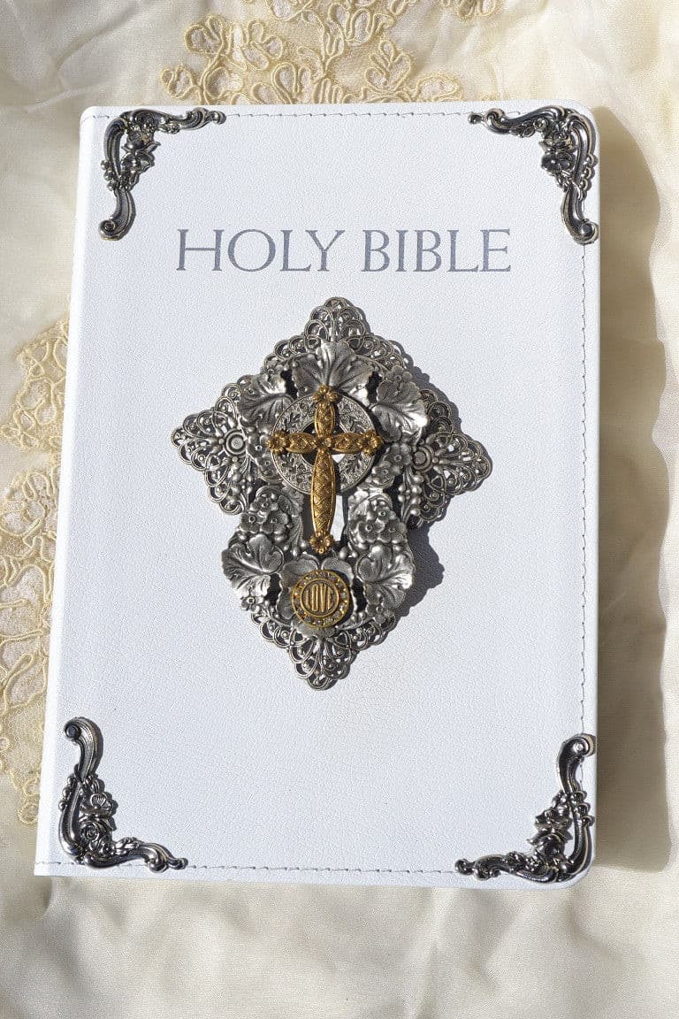 White Catholic bride Bible with ornate silver and gold metal cross on cover, elegant lace background