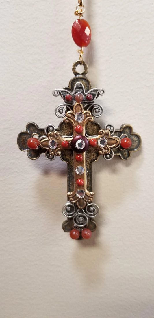Jeweled cross ornament with red and gold accents, clear stones, and ornate detailing