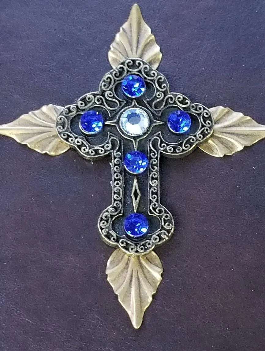Ornate gold cross with blue jewels on a dark leather Bible cover
