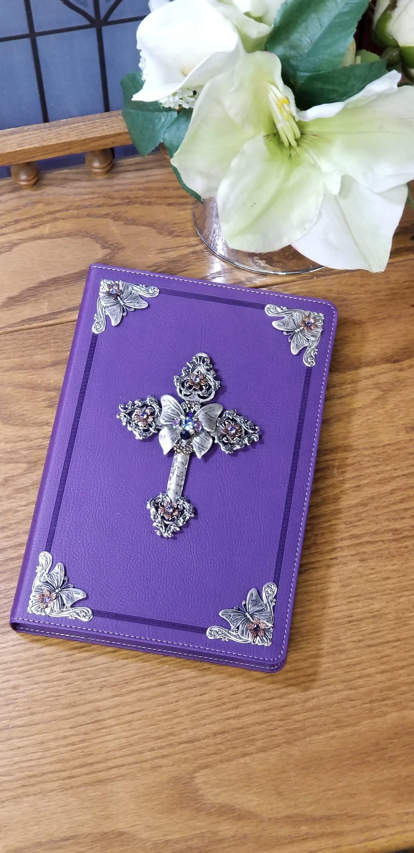 Jeweled KJV Bible with purple cover, ornate cross and butterfly accents on wooden table