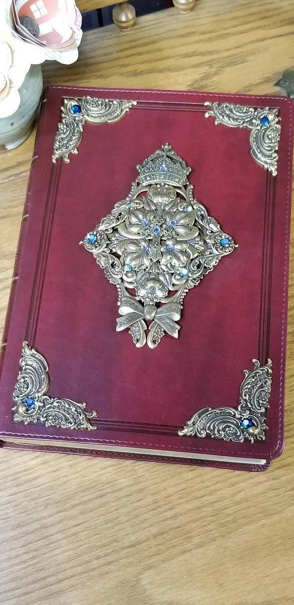 Jeweled KJV Bible with ornate gold and blue embellishments on a red cover, closeup view